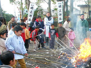 木の棒の先に付けた団子を焼く子供達